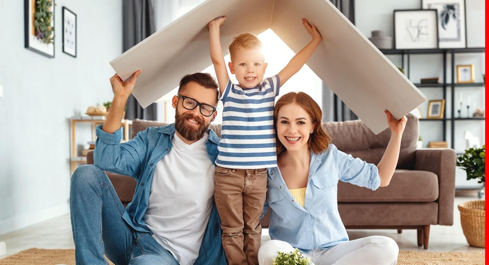 A young family holding a cardboard roof over their heads