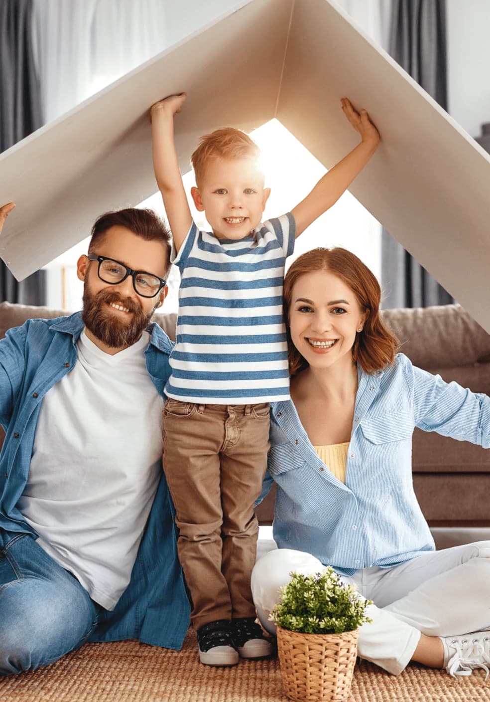 A young family holding a cardboard roof over their heads